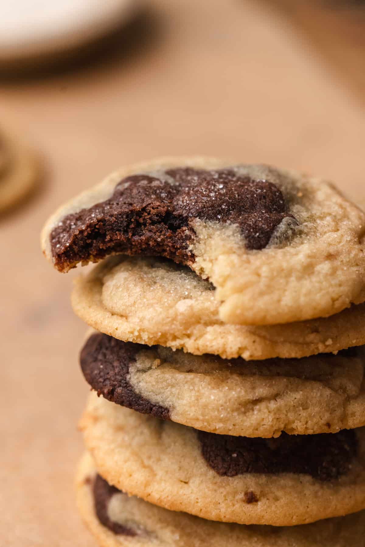 A stack of chocolate marble cookies with a bite taken out of the top cookie.