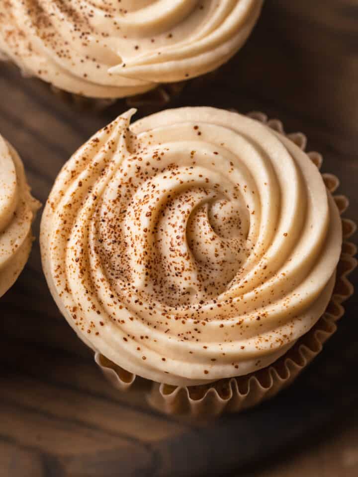 A cupcake dusted with espresso powder on a wood surface.