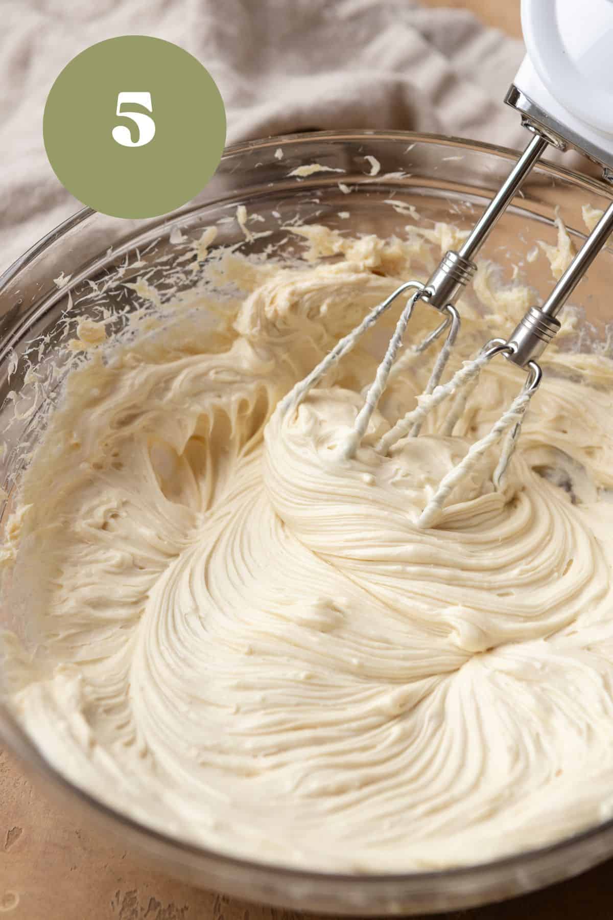 Cream cheese being beat in a large bowl.