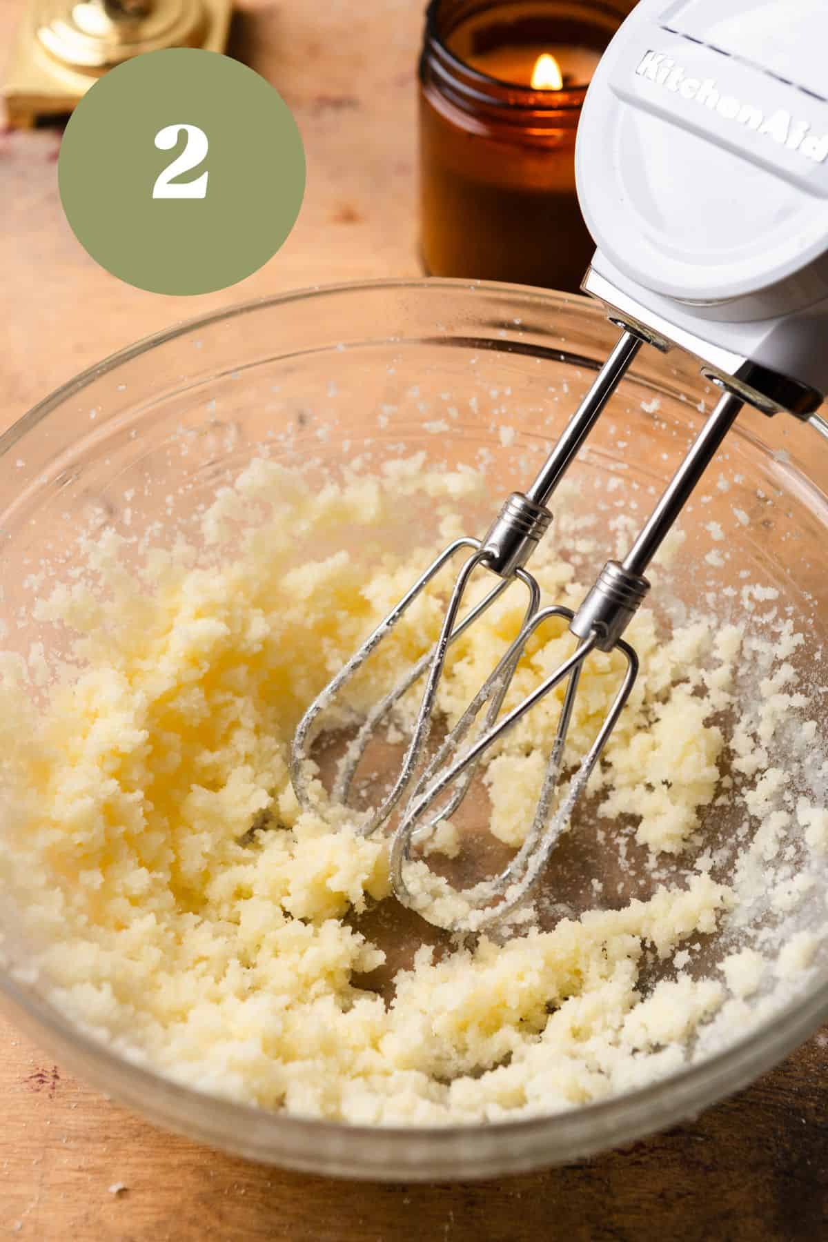 Creaming butter and sugar with a mixer in a glass bowl.