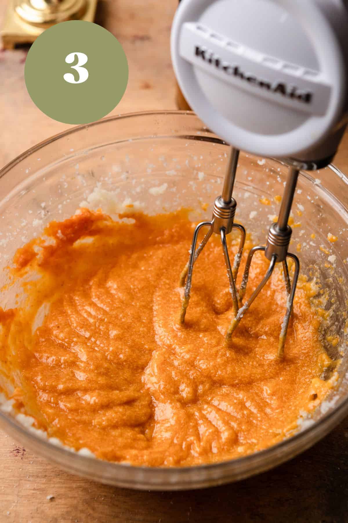 Pumpkin mixed with butter and sugar in a bowl with a handheld mixer.