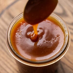 Drizzling salted caramel into a jar off a spoon.