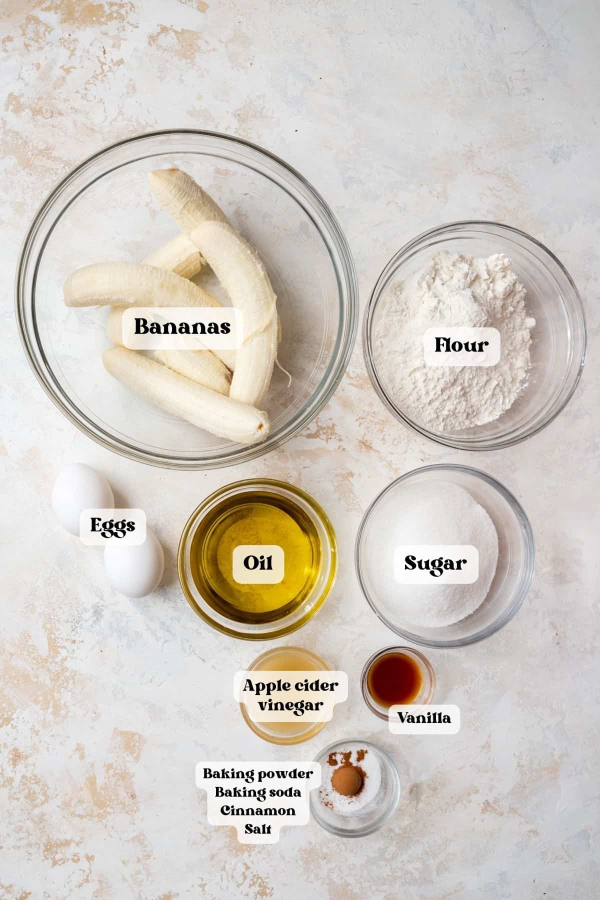 Ingredients to make banana bread on a white surface.