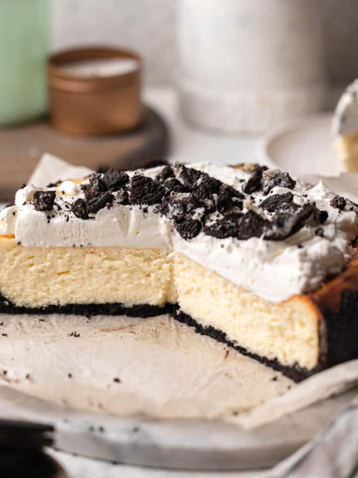 White chocolate Oreo cheesecake cut open on a marble cake stand.