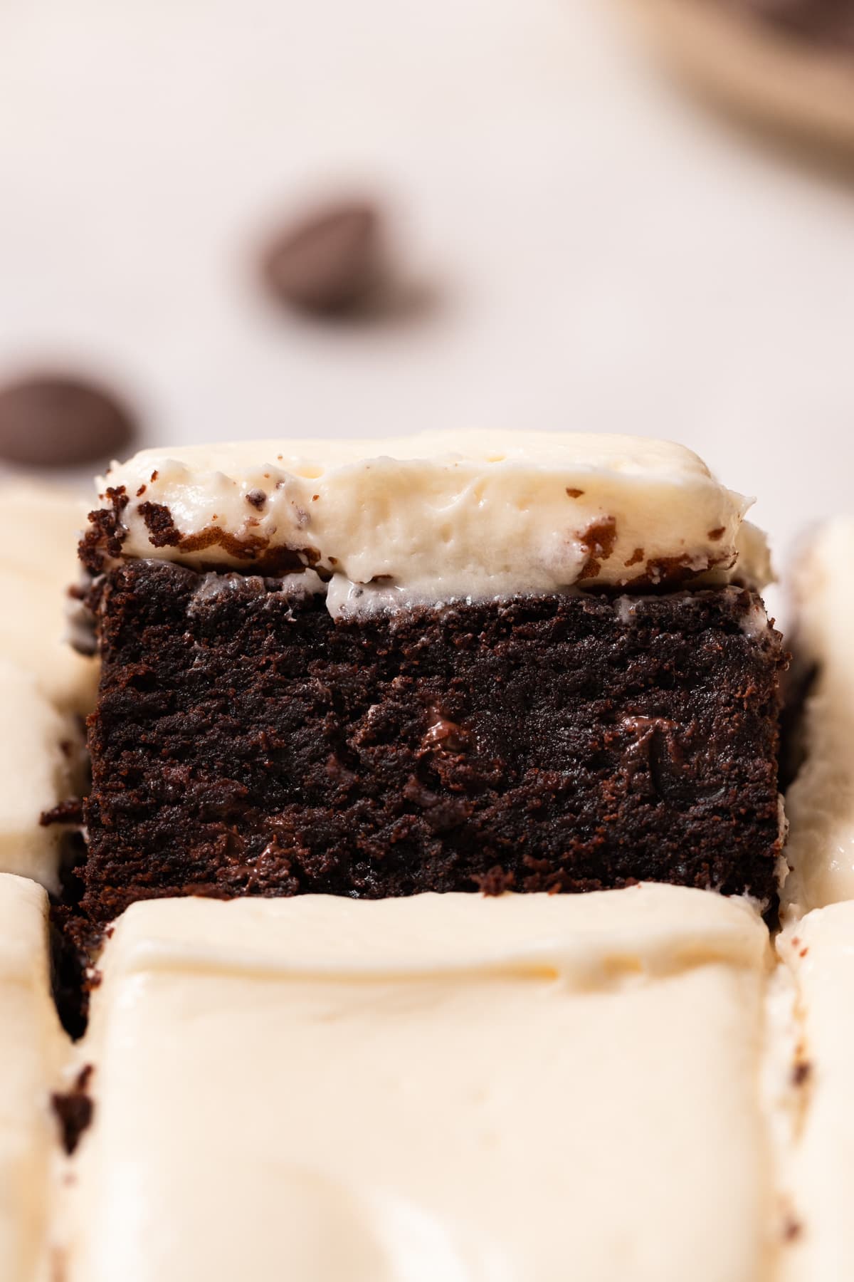 A brownie frosted with cream cheese frosting on a white surface.