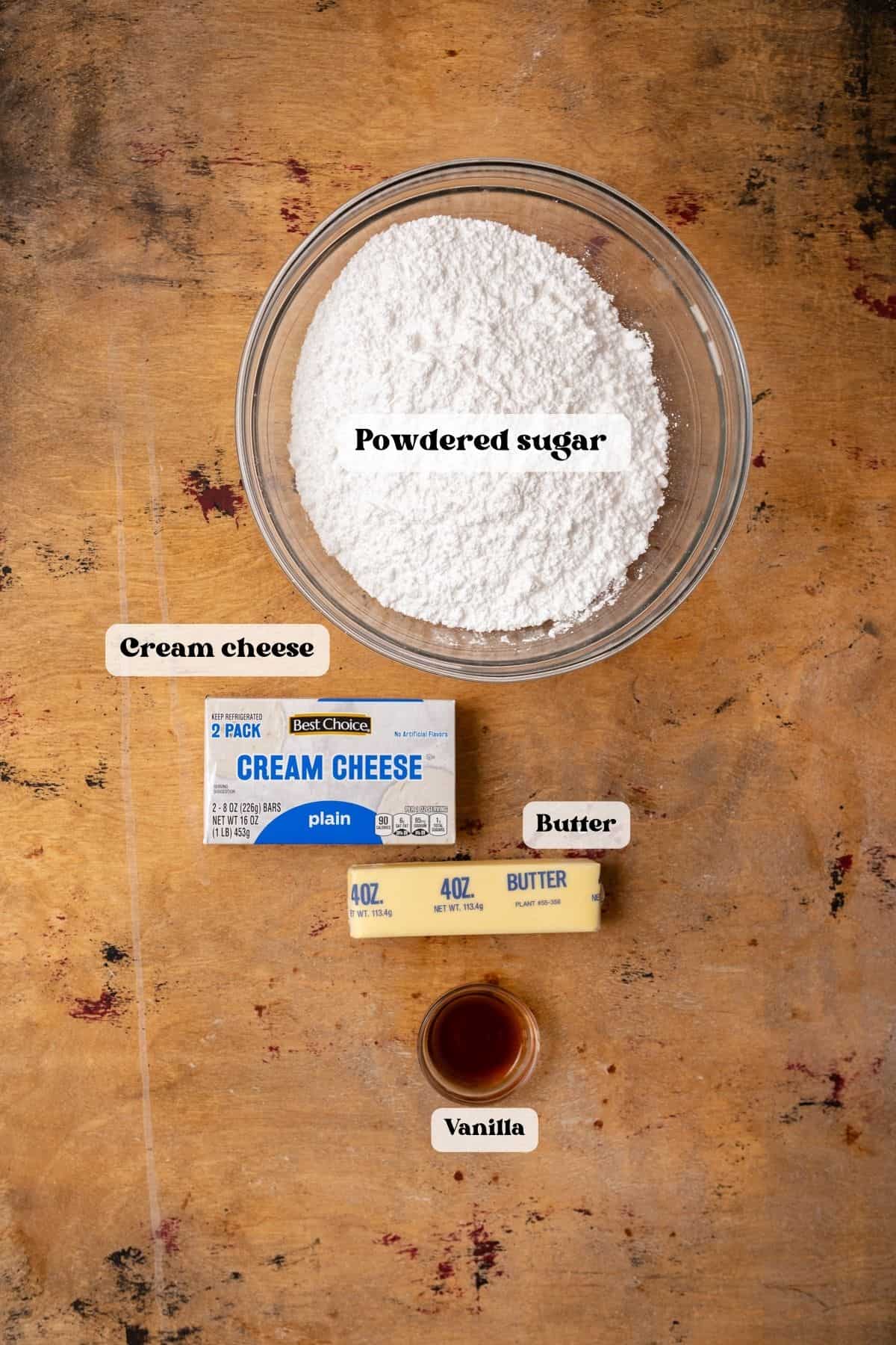 Ingredients to make cream cheese frosting on a wood surface.