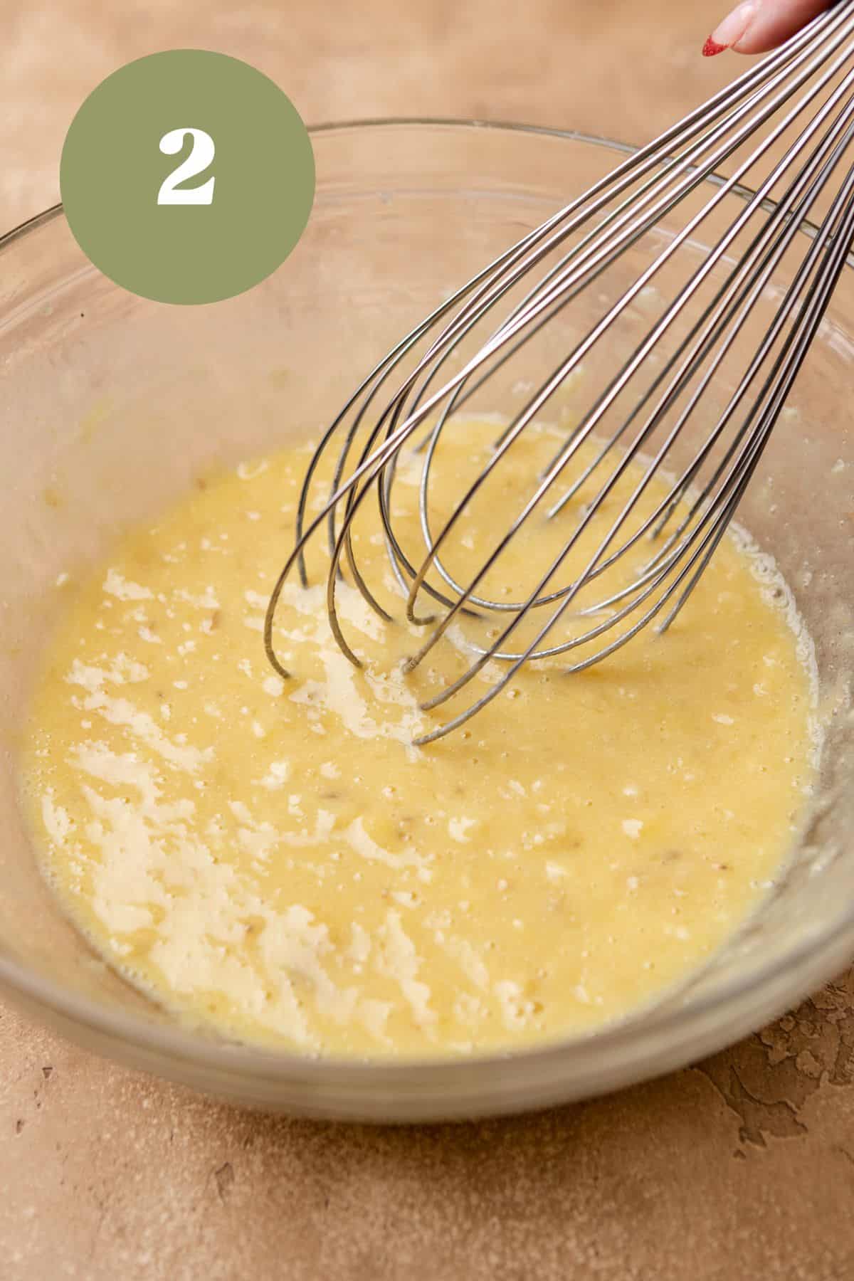 Wet ingredients for banana bars in a bowl with a whisk.