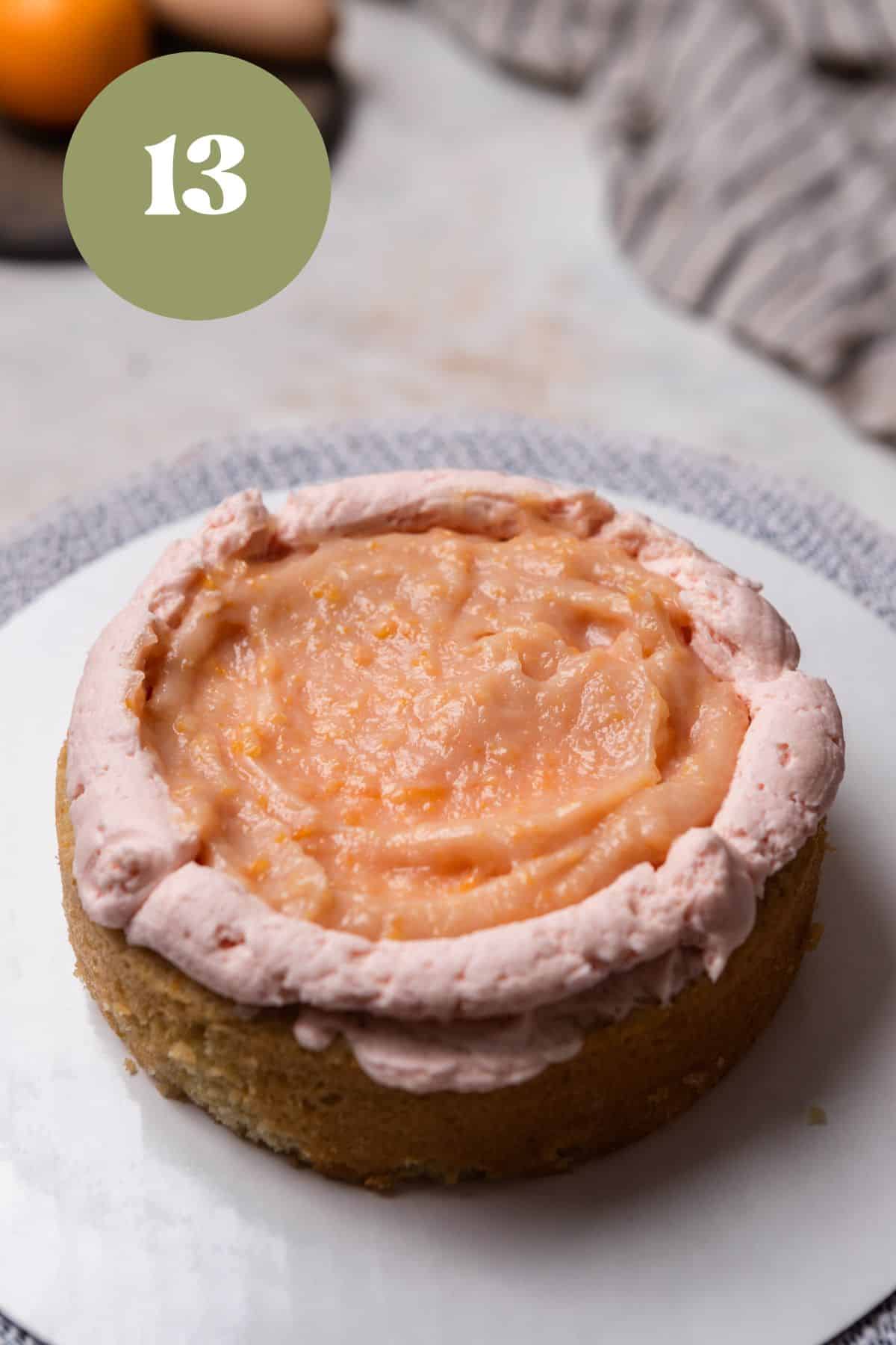 A cake layer with blood orange curd and orange buttercream around it.