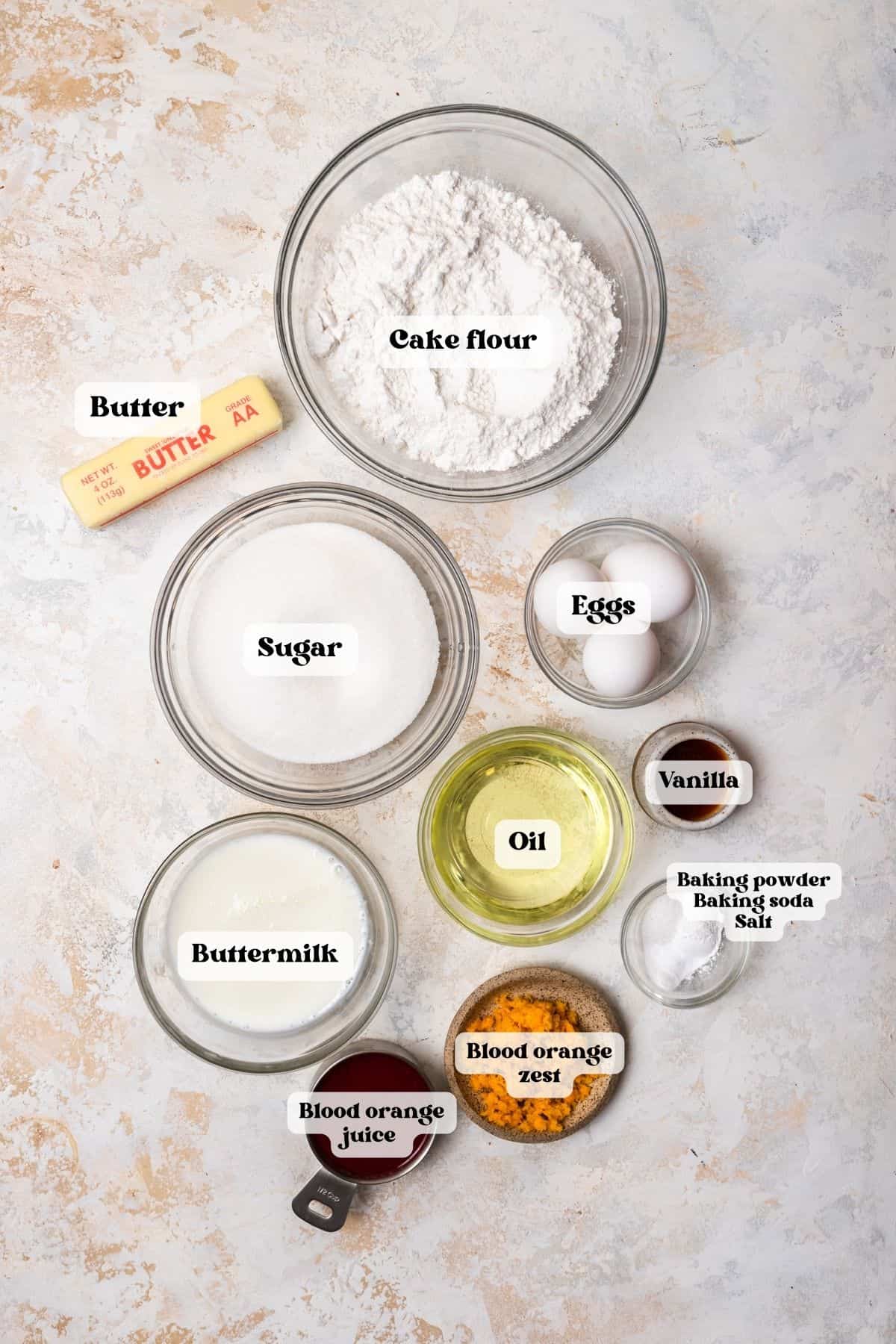 Ingredients to make blood orange cake on a white surface.