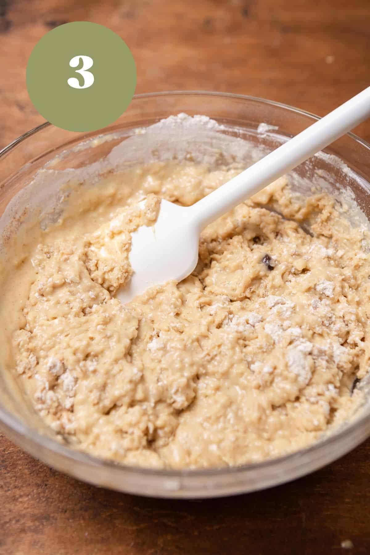 Muffin batter in a large bowl with a rubber spatula.
