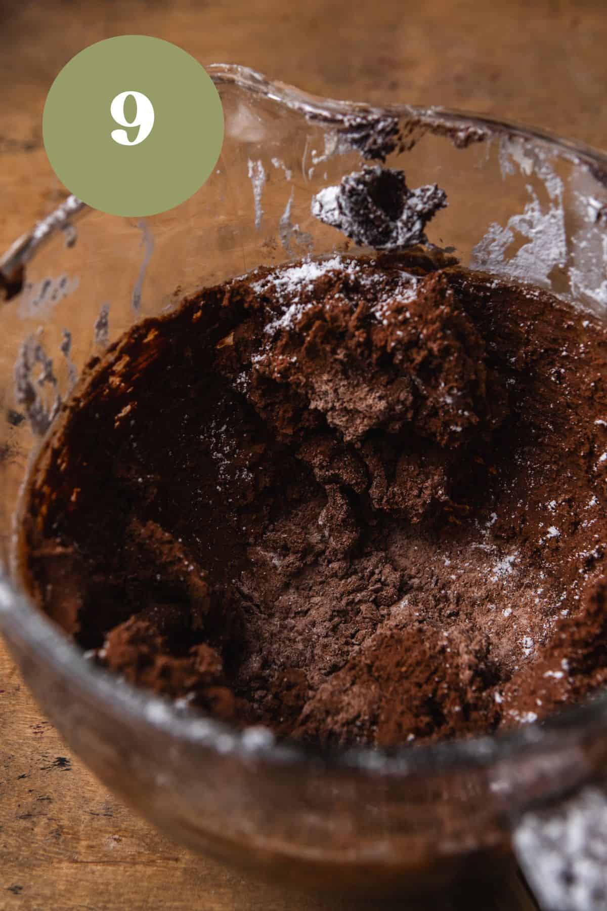 Butter, cocoa powder, and powdered sugar mixed together in a glass bowl.