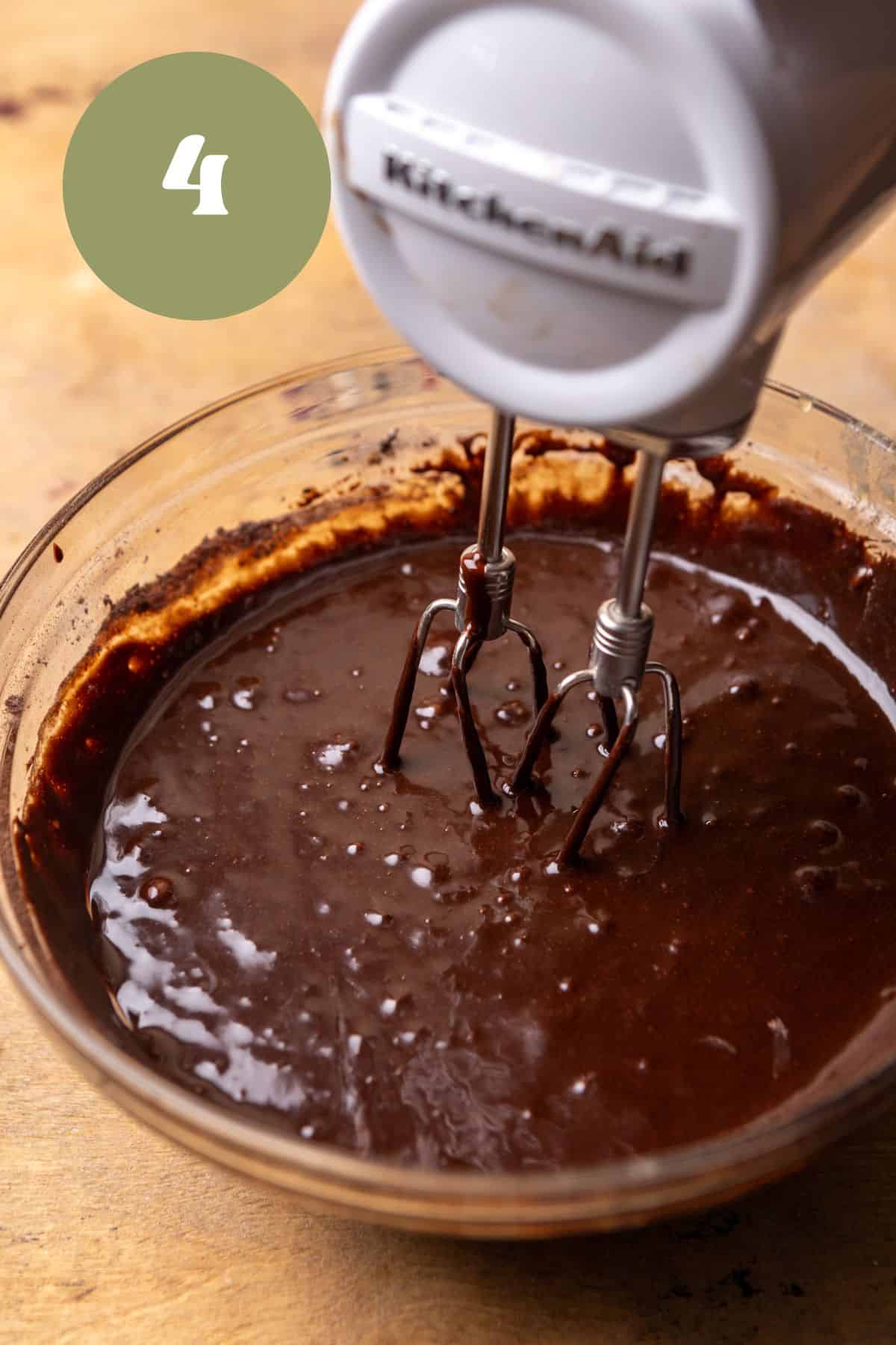 Brownie batter in a bowl with a hand mixer.