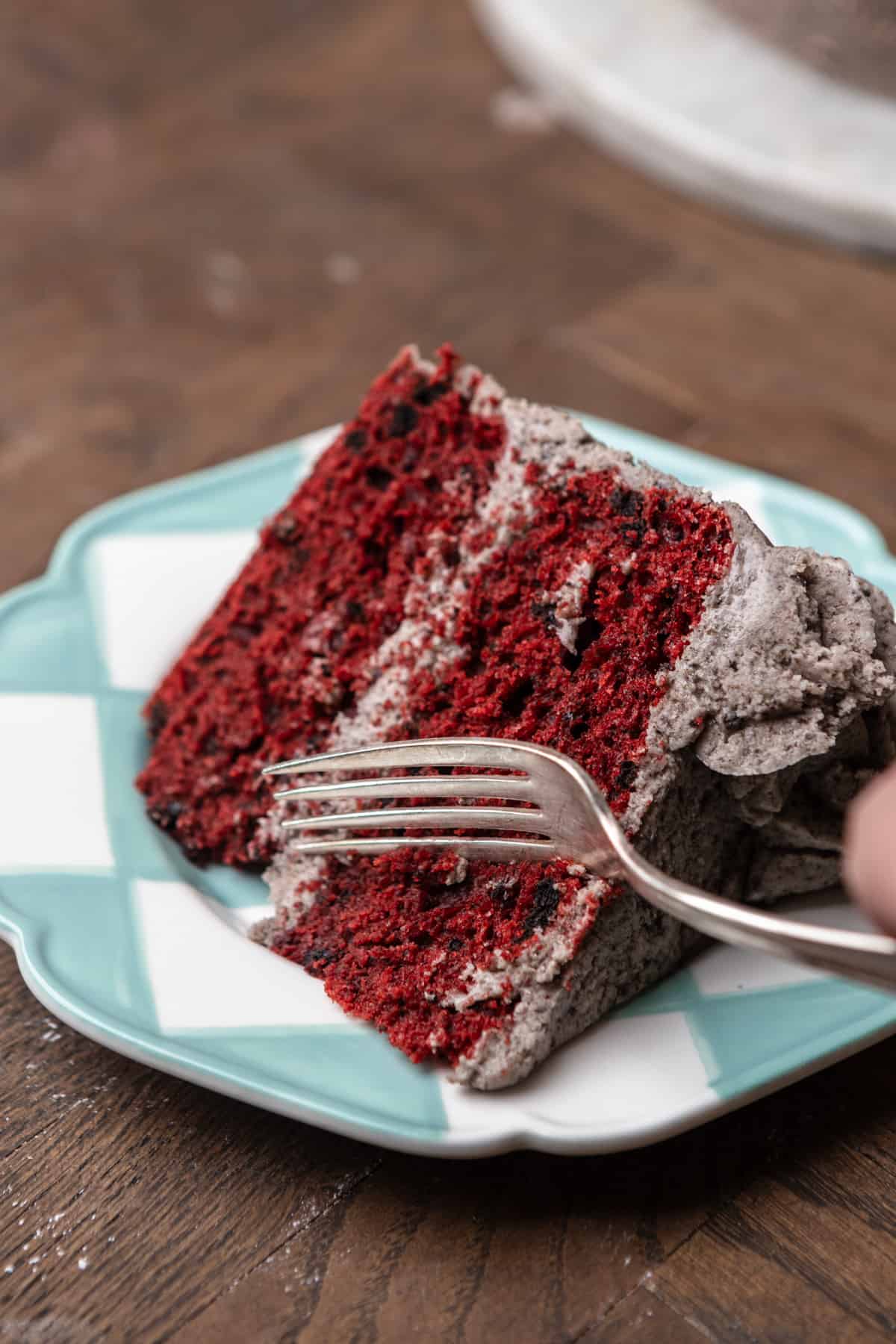 A slice of red velvet oreo cake on a plate with a fork cutting into it.