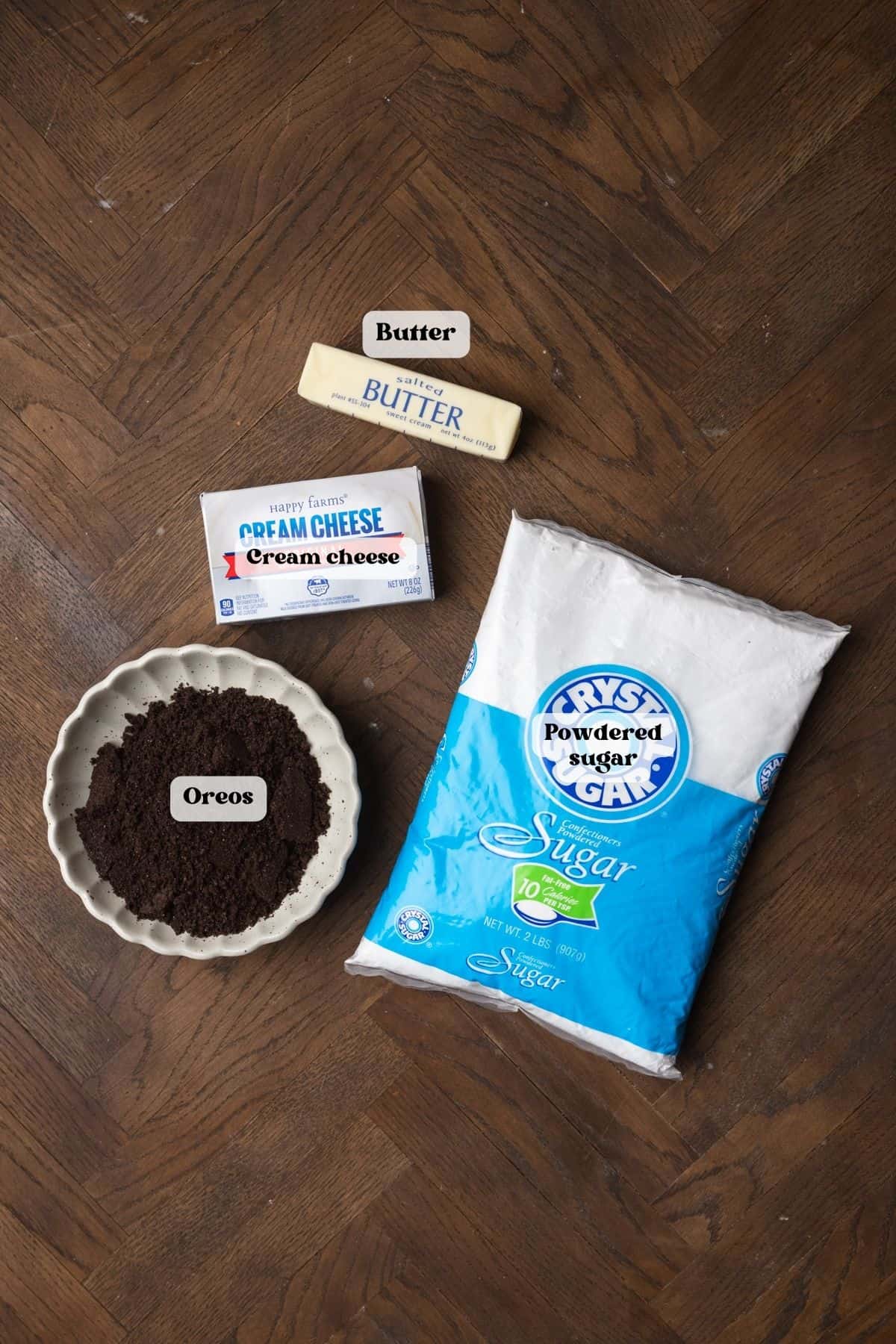 Ingredients to make oreo cream cheese frosting on a wood surface.