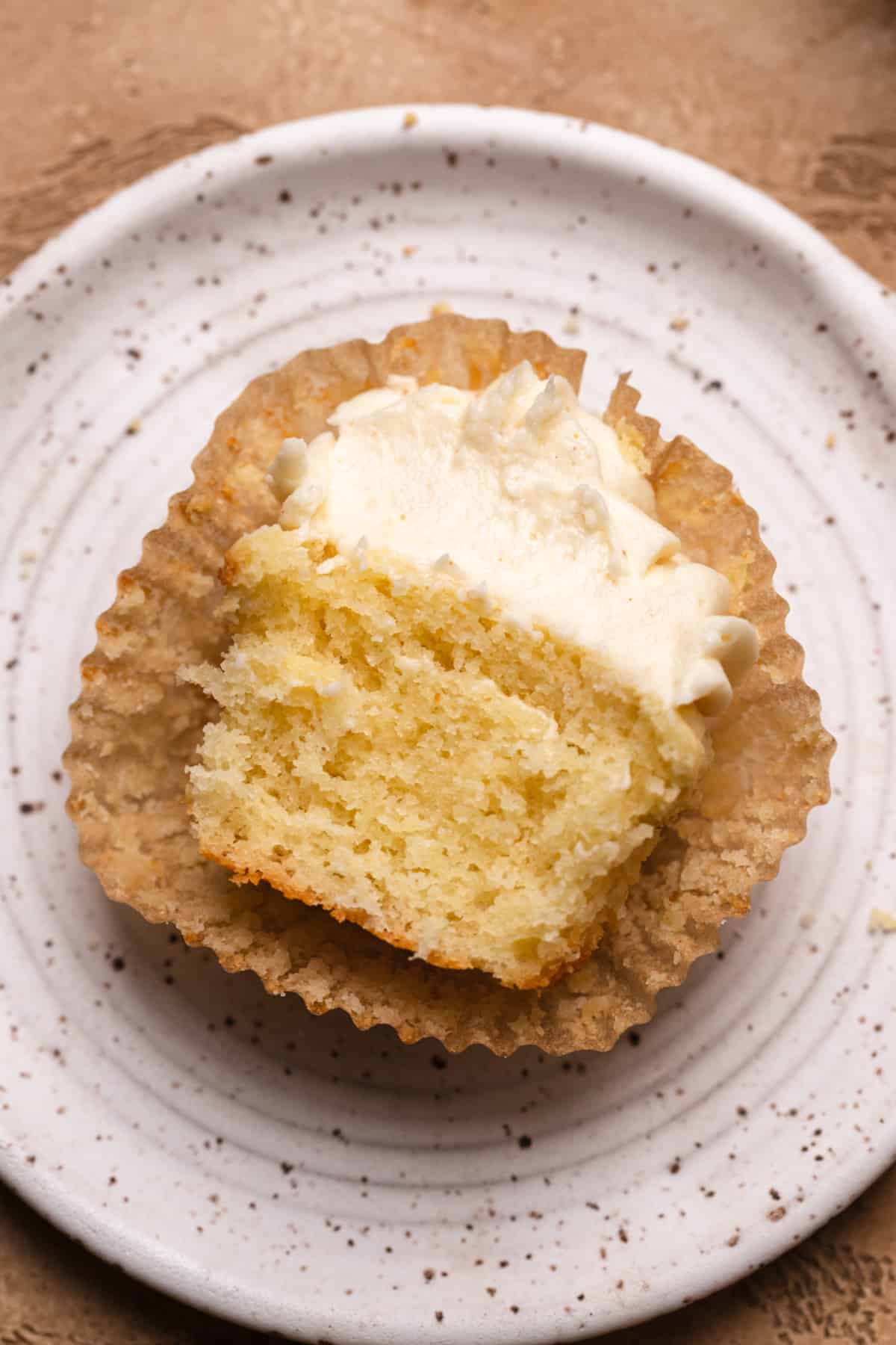 A vanilla cupcake made with oil cut in half on a white plate.
