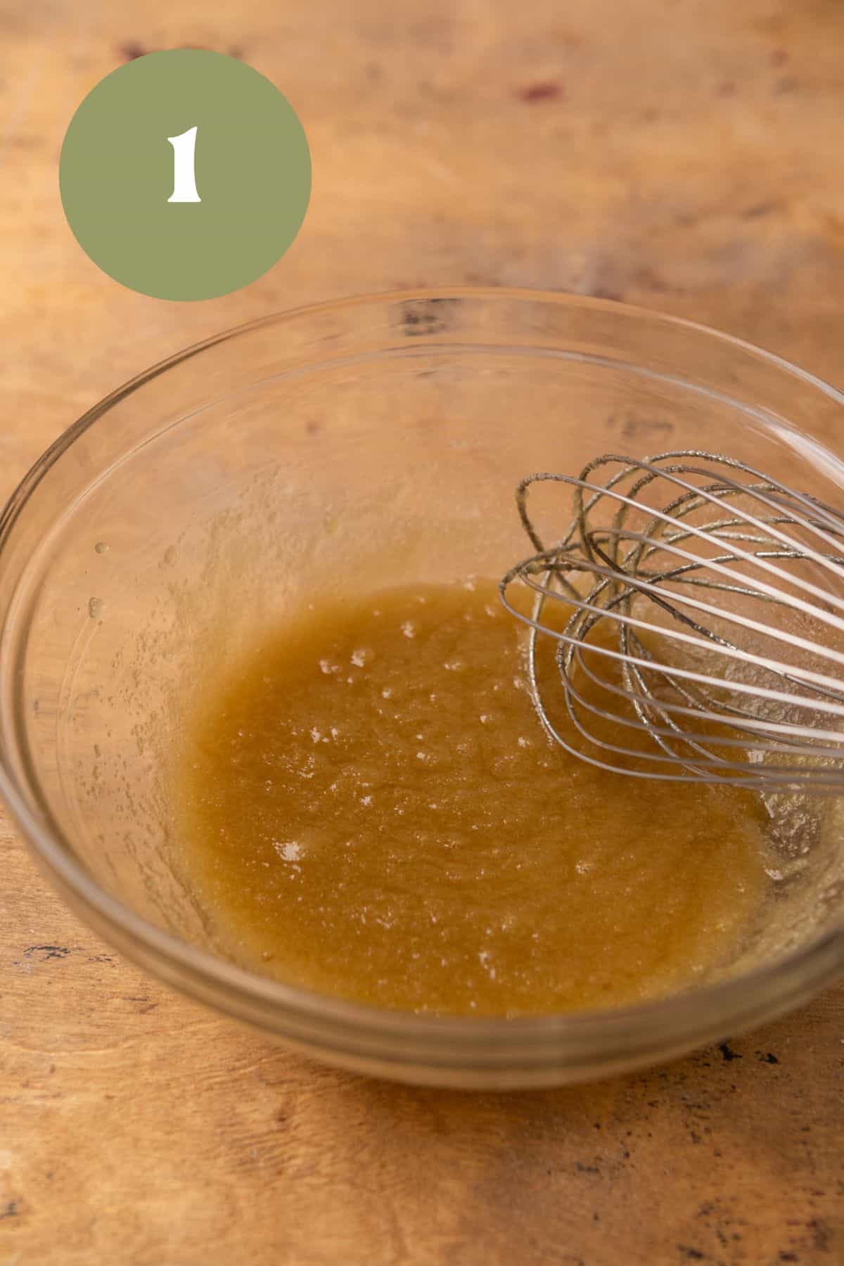 Melted butter and sugar mixed in a bowl with a whisk.
