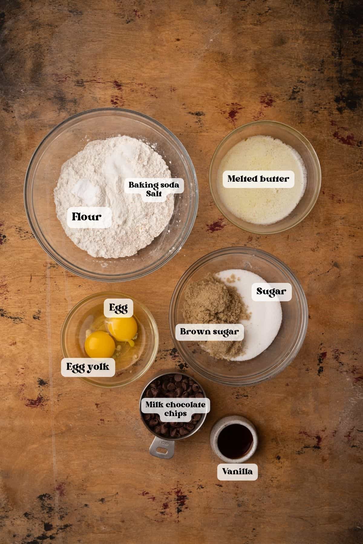 Ingredients to make cookies in bowls on a wood surface.