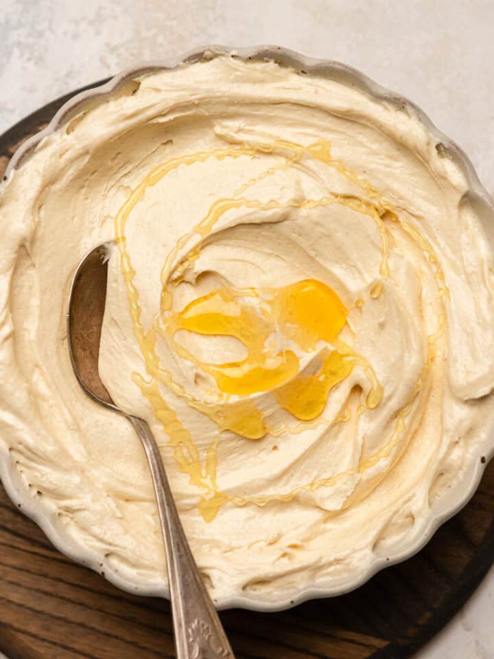 Frosting in a bowl with a spoon with a honey drizzle.