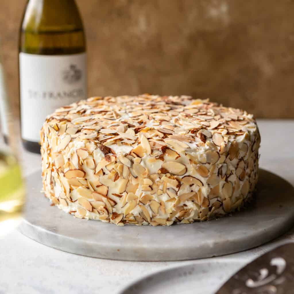 A cake covered in sliced almonds on a white plate.