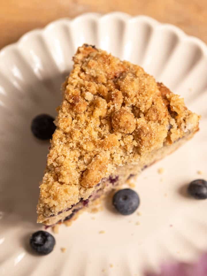 A close up of a blueberry muffin cake slice on a plate.