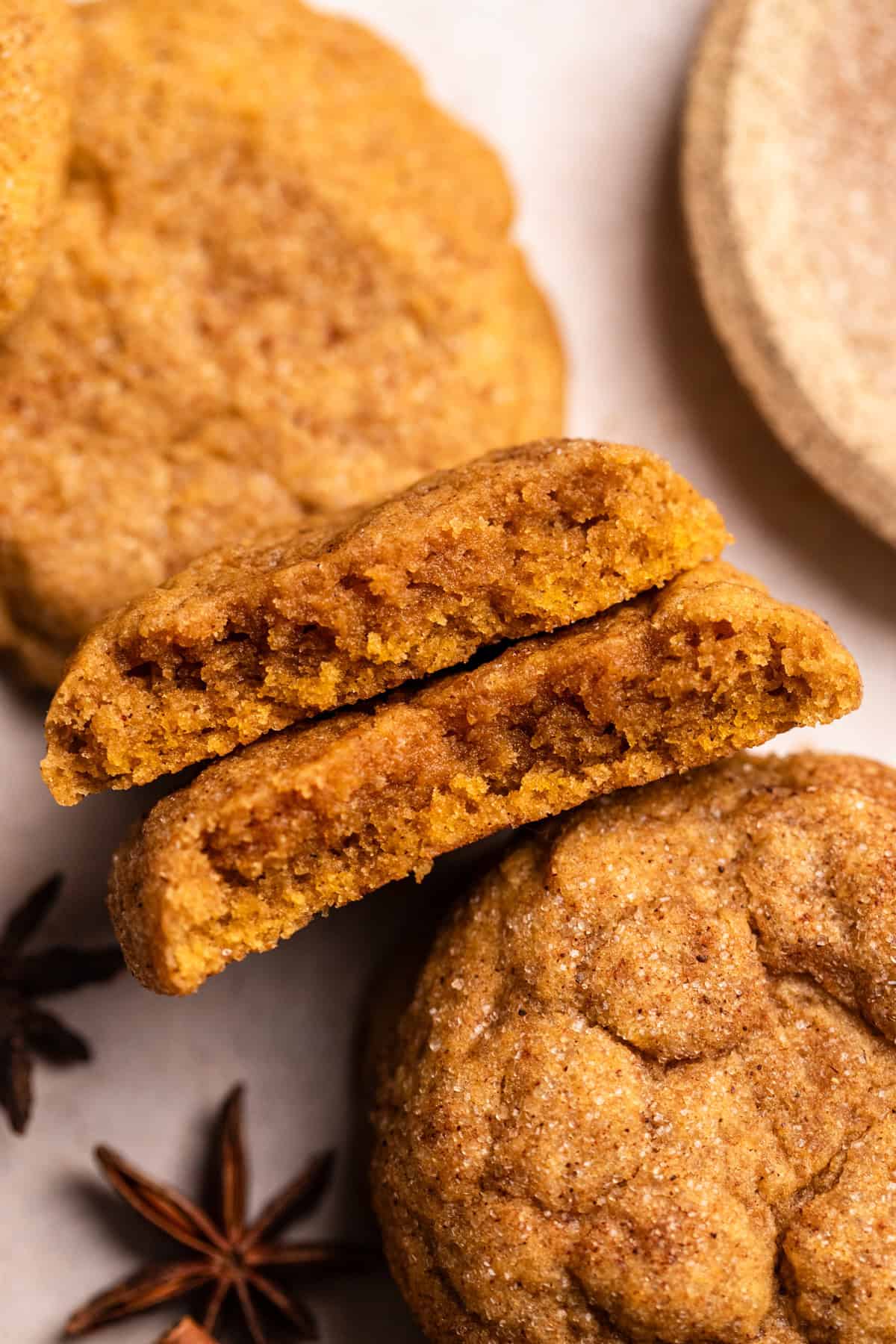 Two halves of a pumpkin spice cookie on parchment paper.
