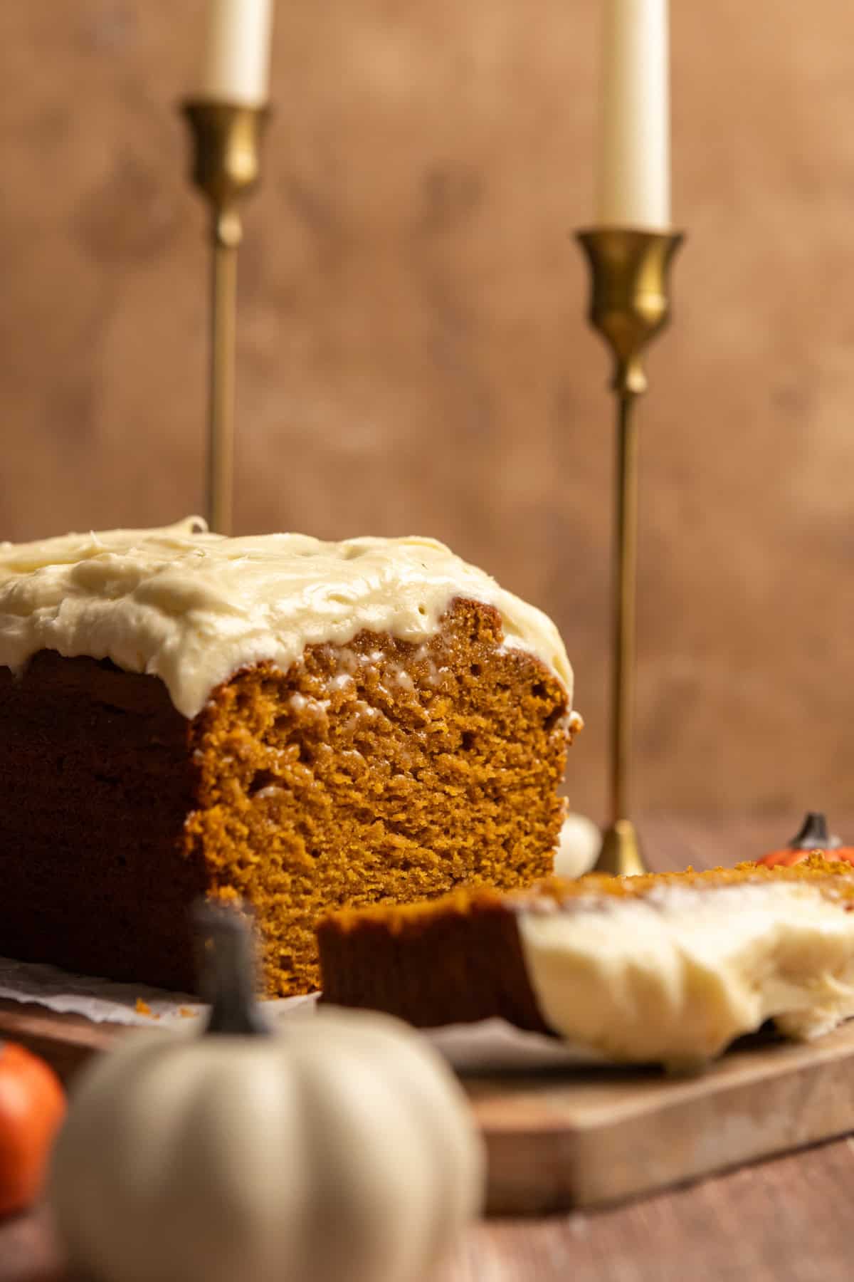 Pumpkin bread with cream cheese frosting cut open on a serving board.