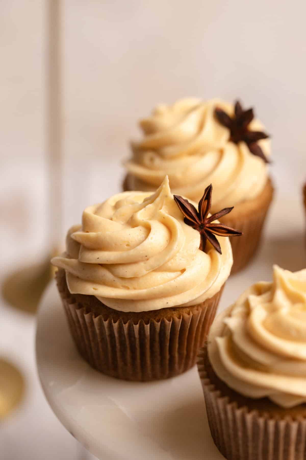 Pumpkin cupcakes on a cake stand garnished with star anise.