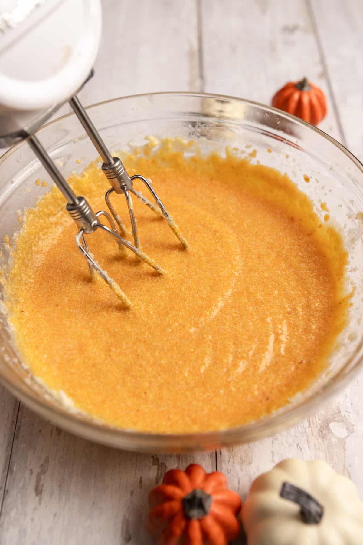 Pumpkin puree added to wet ingredients in a glass bowl.