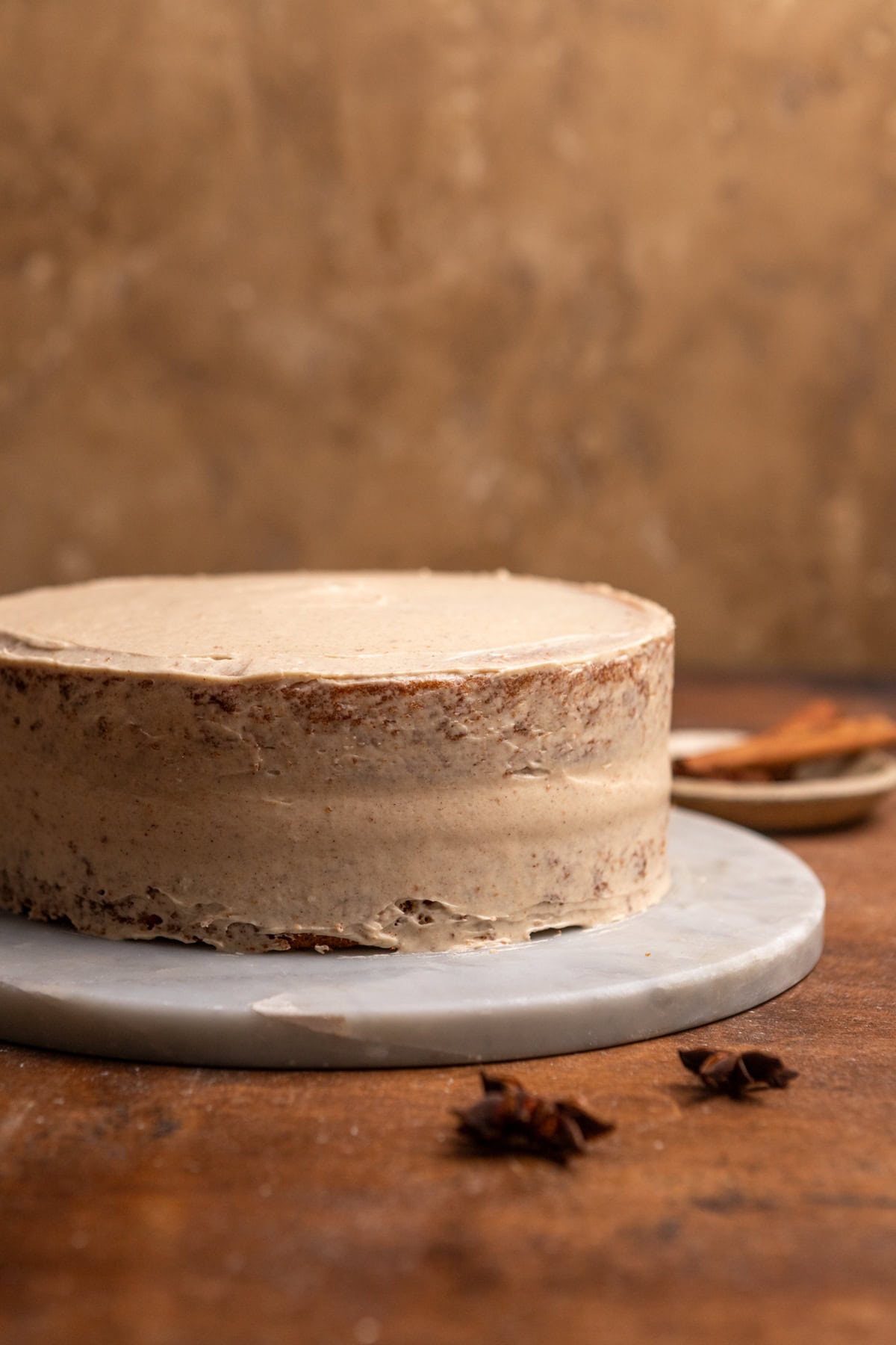 A cake on a marble platter with a crumb coat of frosting.