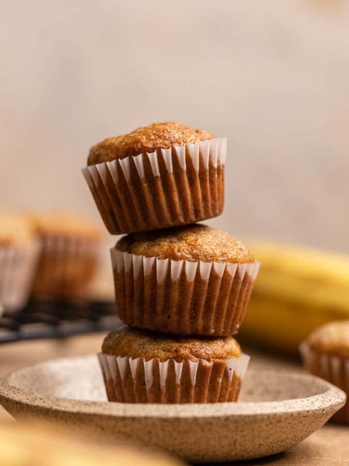 Three banana bread mini muffins stacked on top of each other.