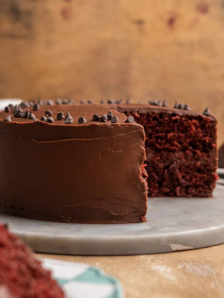 Cut open chocolate frosted cake on a marble plate.
