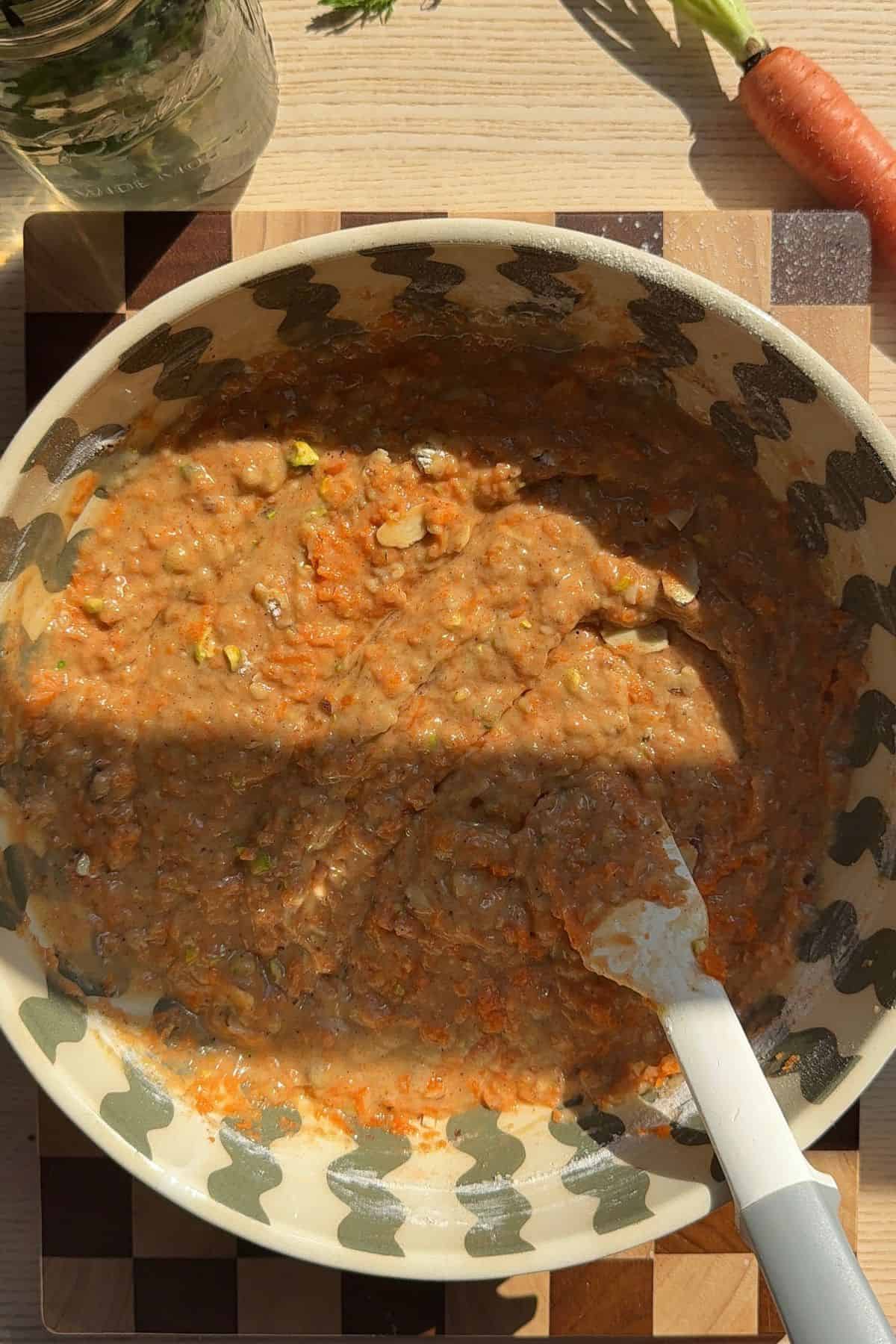 Carrot cake muffin batter in a large bowl with a rubber spatula.