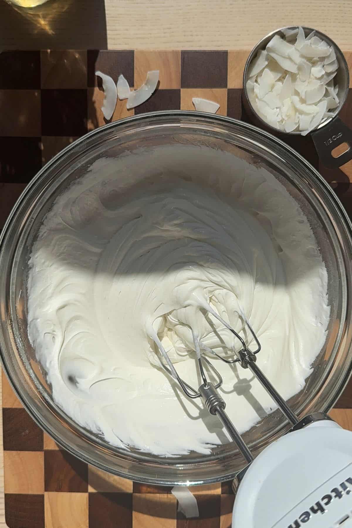 Whipping coconut ganache with a handheld mixer.