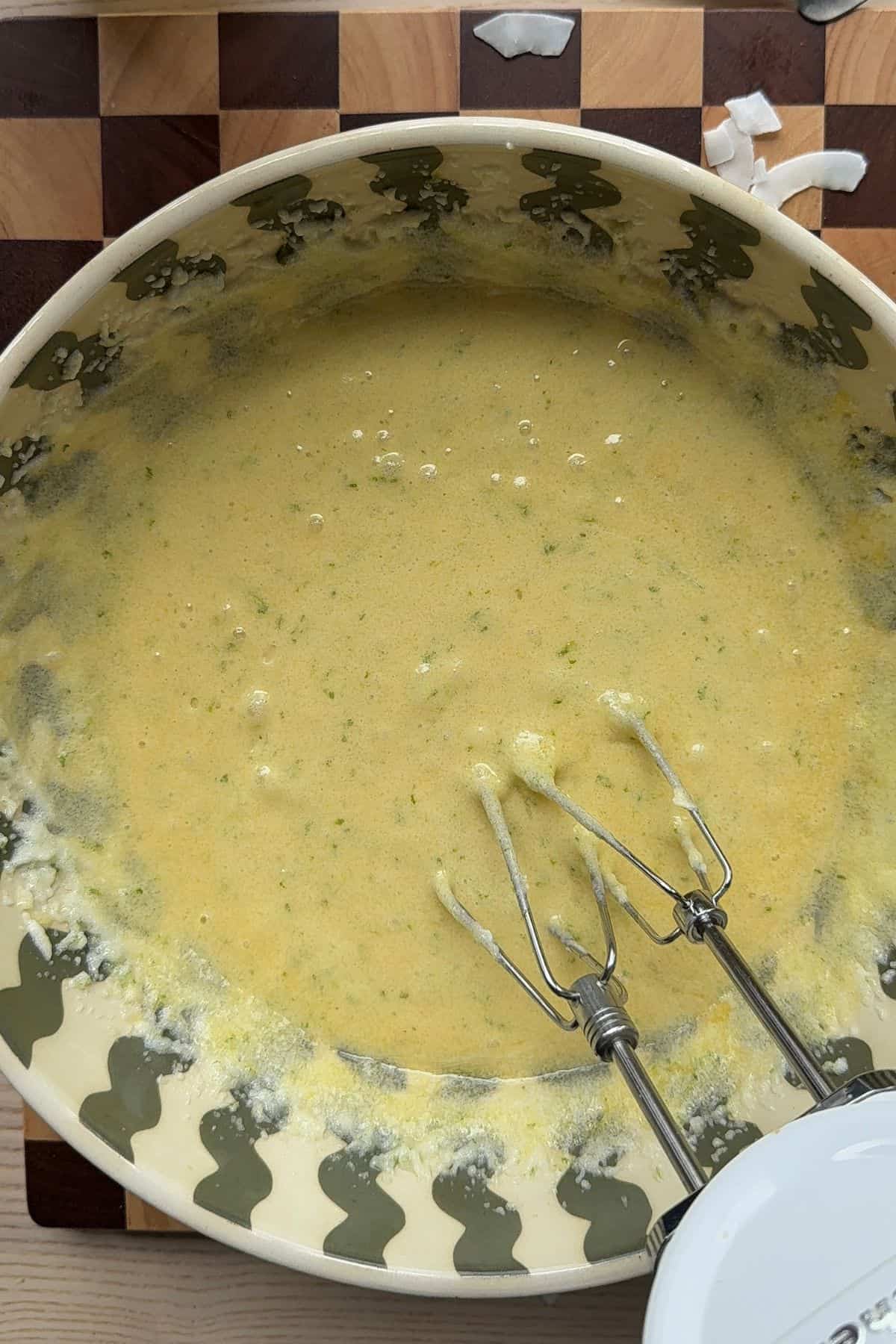 Butter, lime zest, and sugar mixed with eggs in a large bowl.