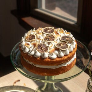 A coconut lime layer cake on a green glass cake stand.