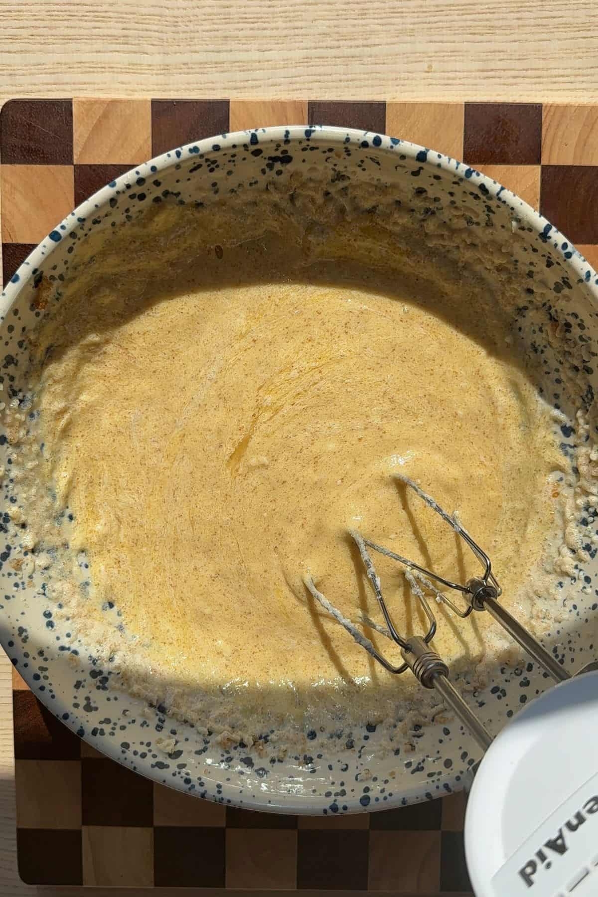 Eggs, butter, and sugar combined in a large bowl with a mixer.