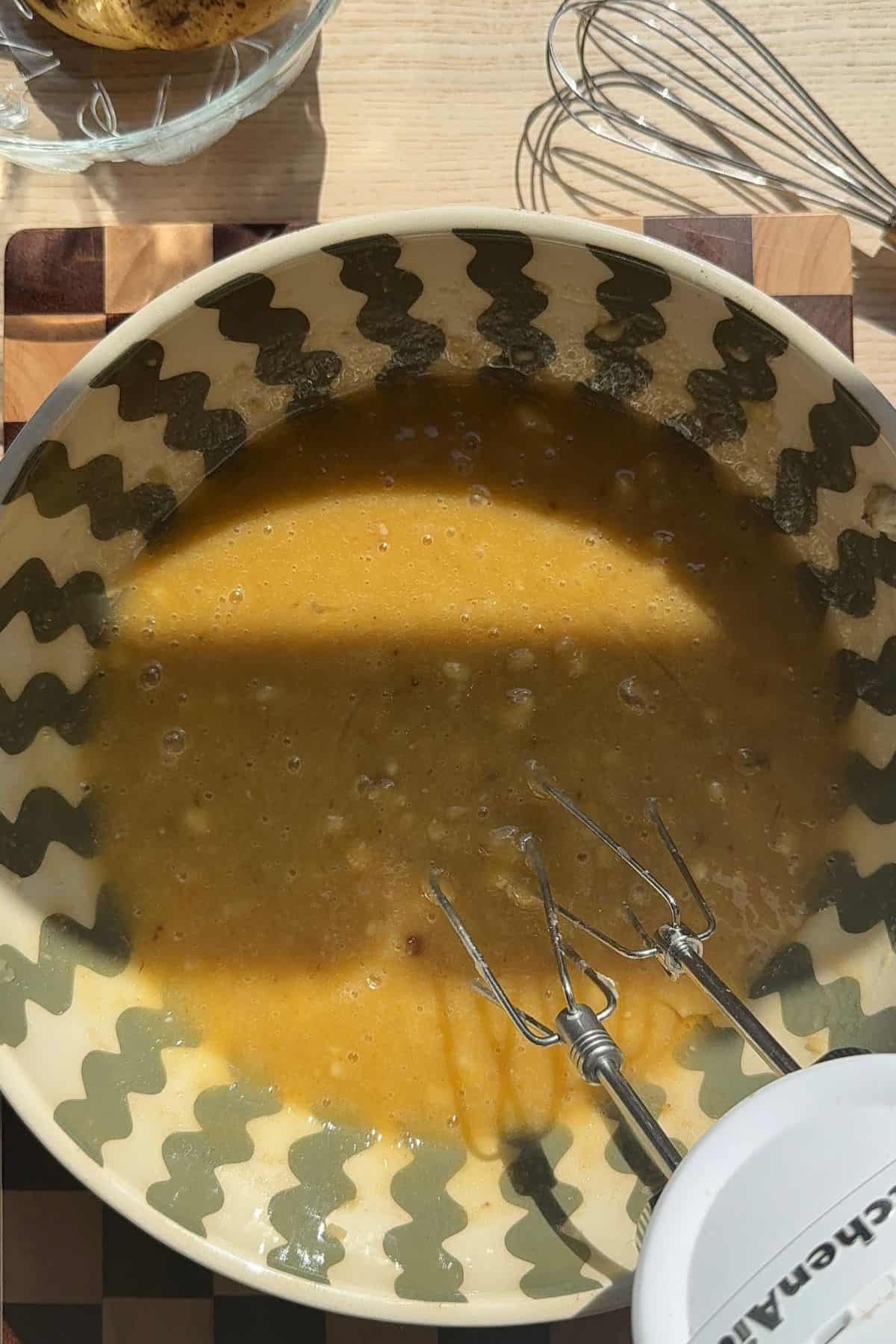 Mashed bananas mixed with sugar in a mixing bowl.