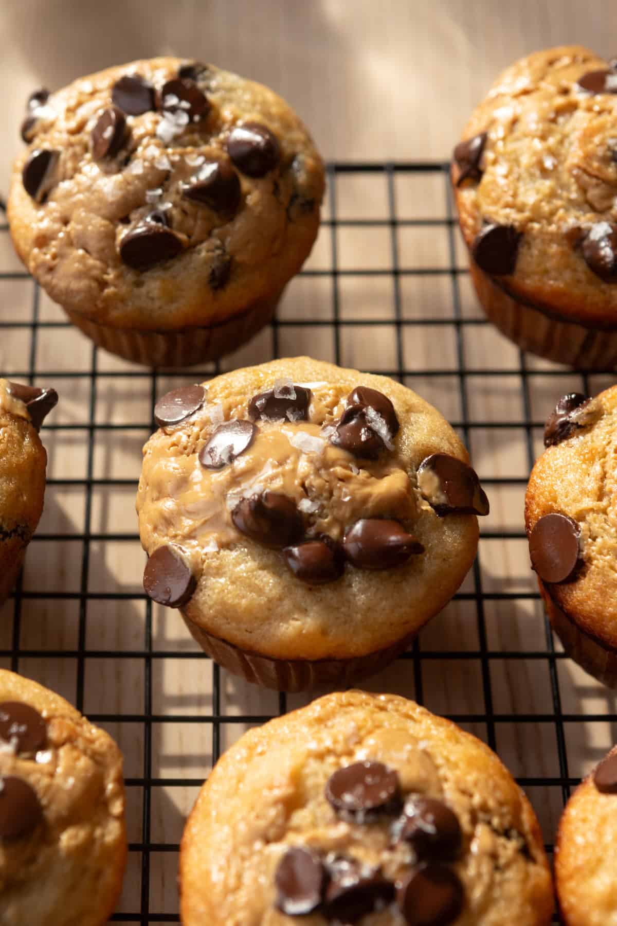 Peanut butter banana bread muffins with chocolate chips on a cooling rack.