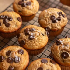 Peanut butter banana bread muffins with chocolate chips on a wire rack.