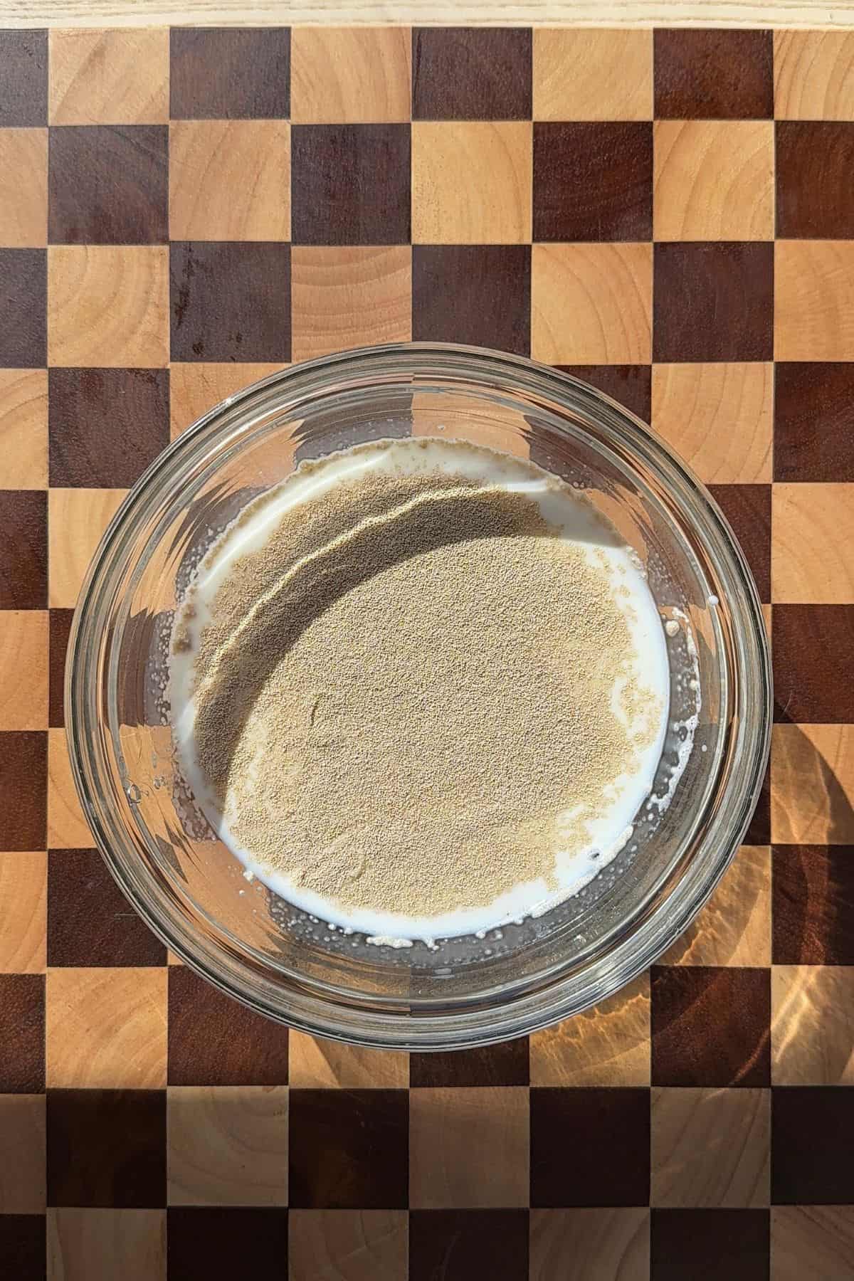 A bowl of milk with yeast sprinkled on top.