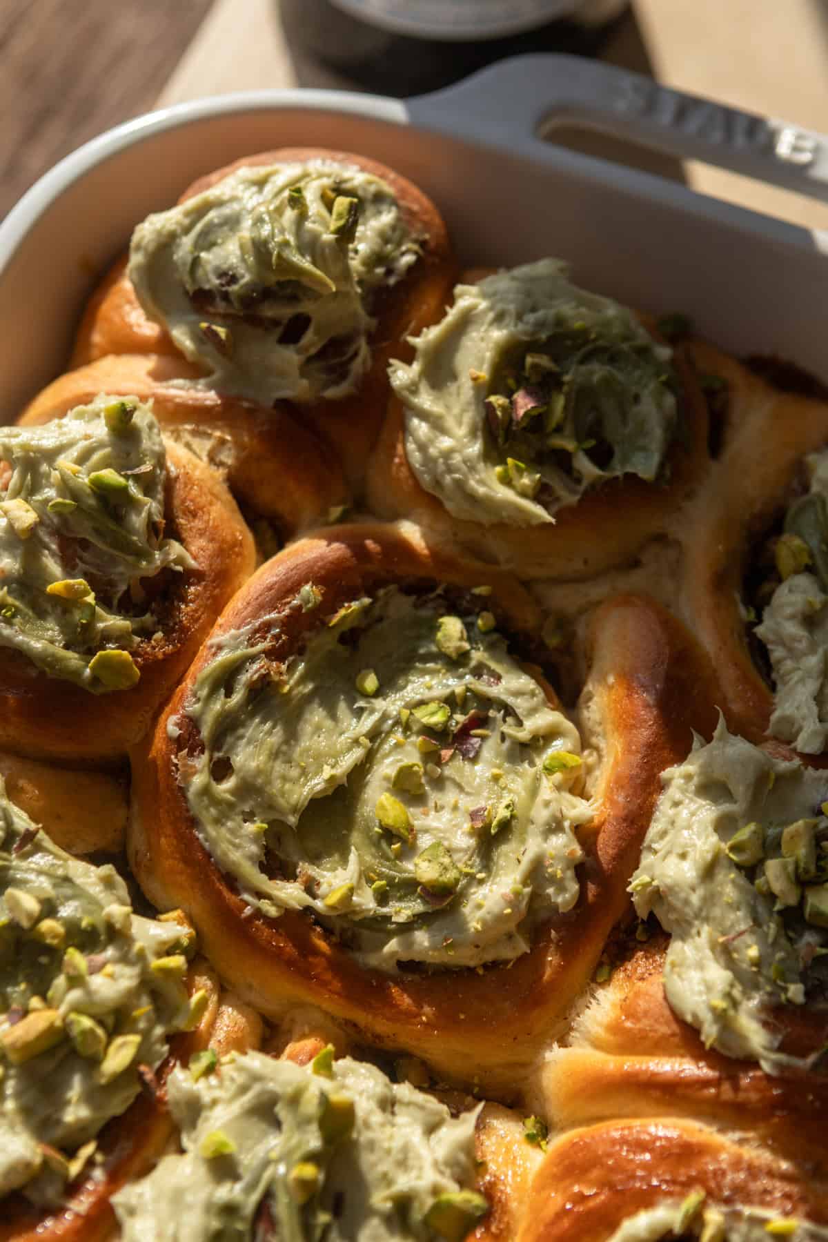 Pistachio cinnamon rolls in a baking dish.