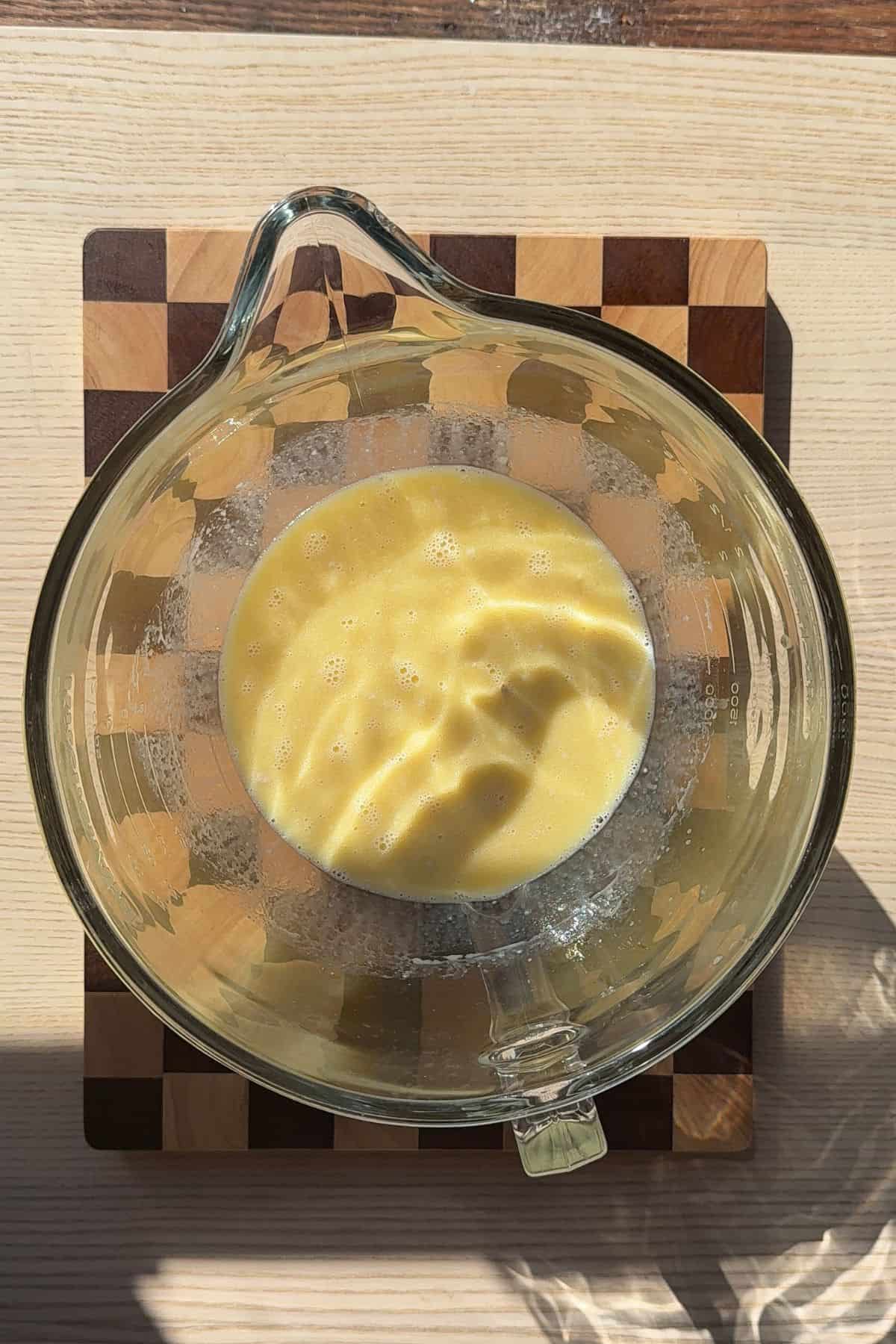 Milk, sugar, and eggs combined in a large bowl.