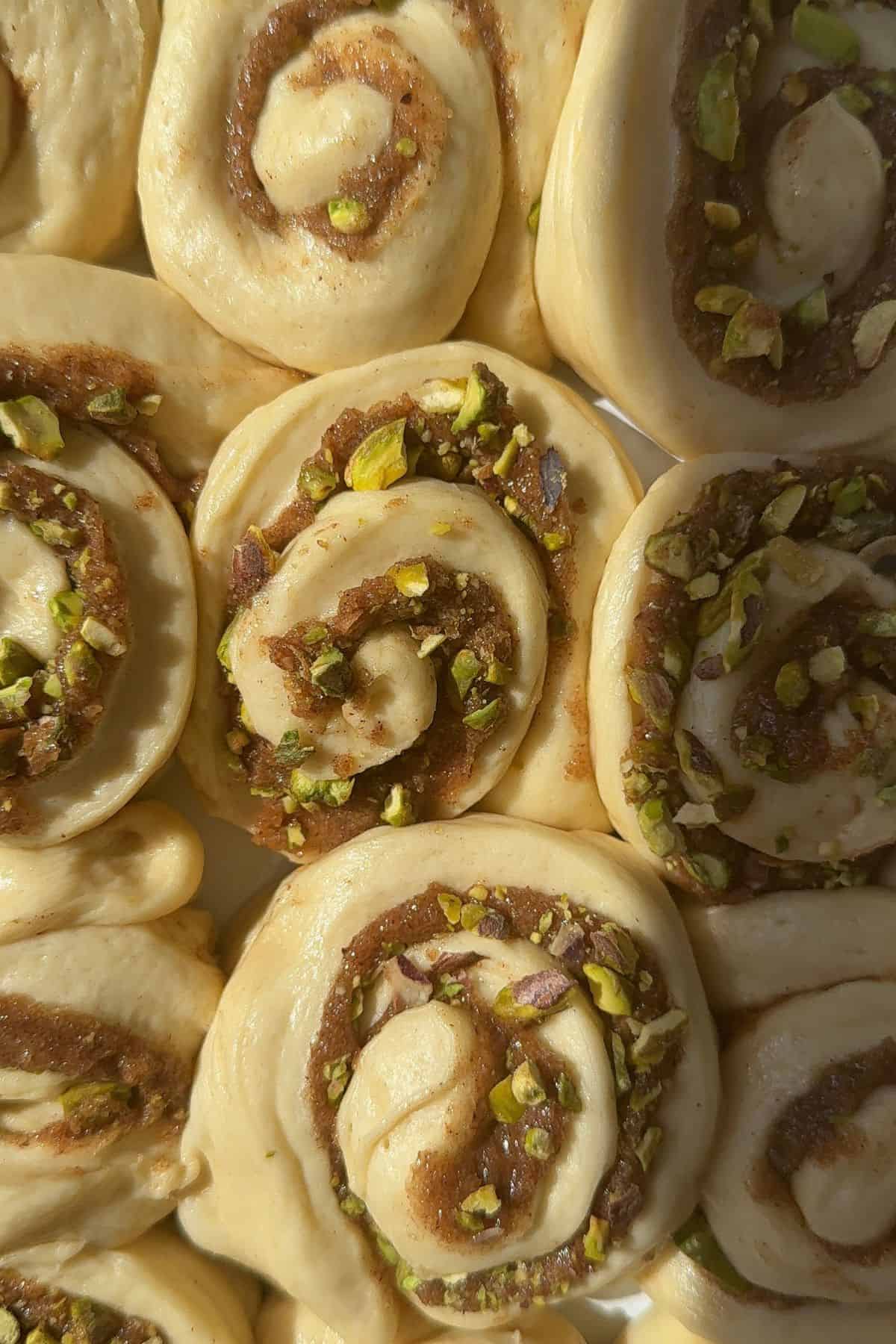 Unbaked pistachio cinnamon rolls in a dish.