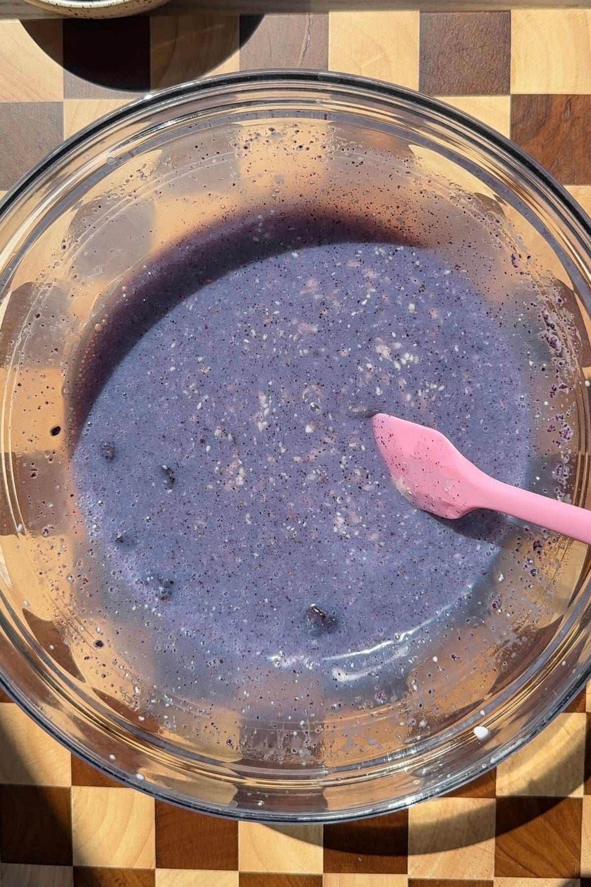 Blueberry ganache in a bowl with a spatula.