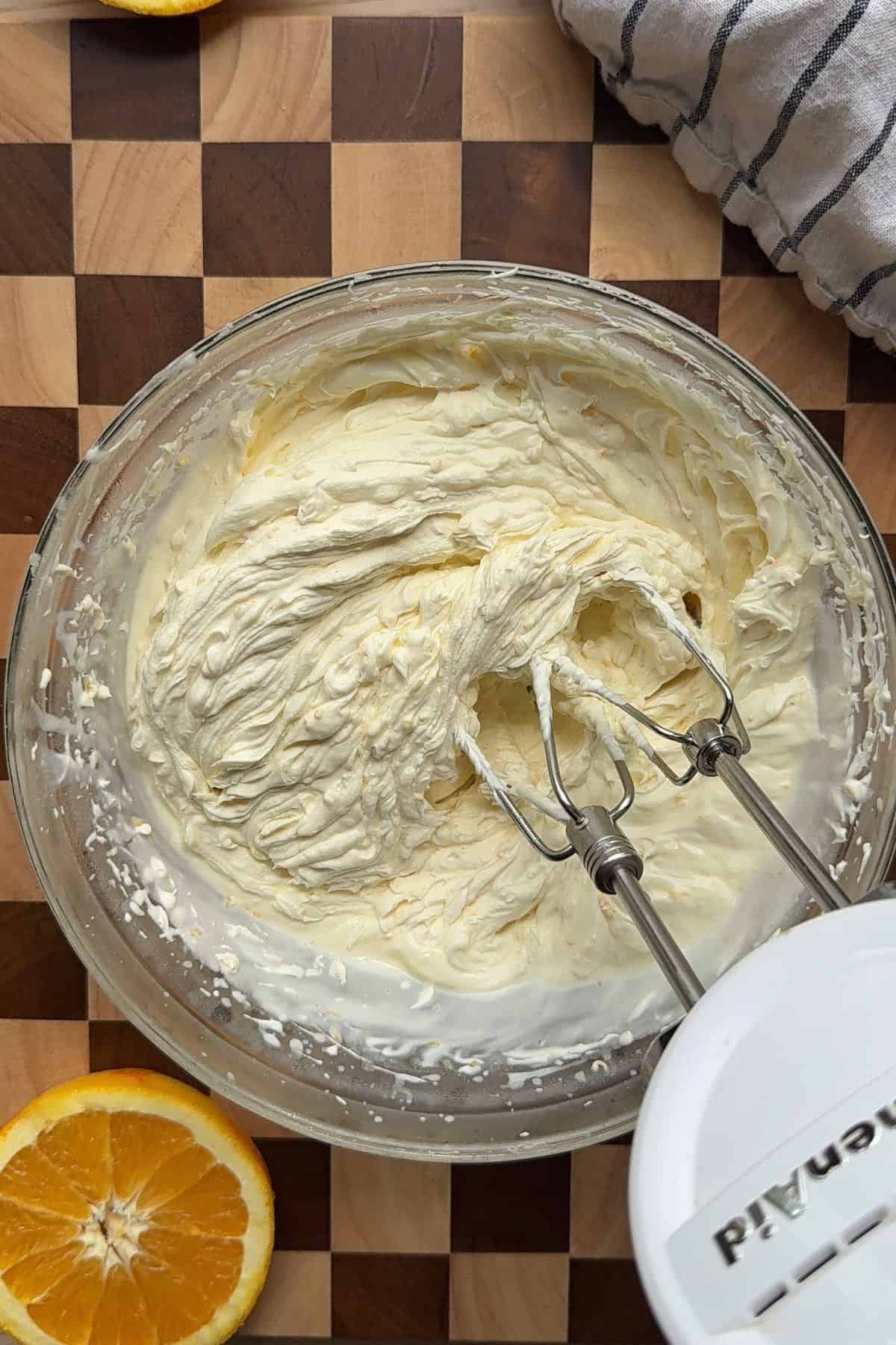 Whipped frosting in a bowl with a hand mixer.