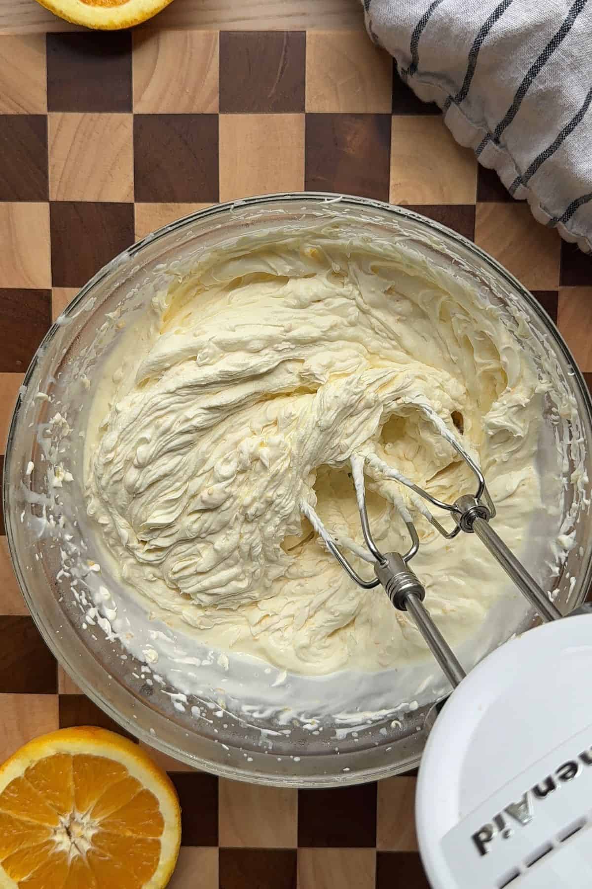 Whipped white chocolate orange ganache in a large glass bowl.