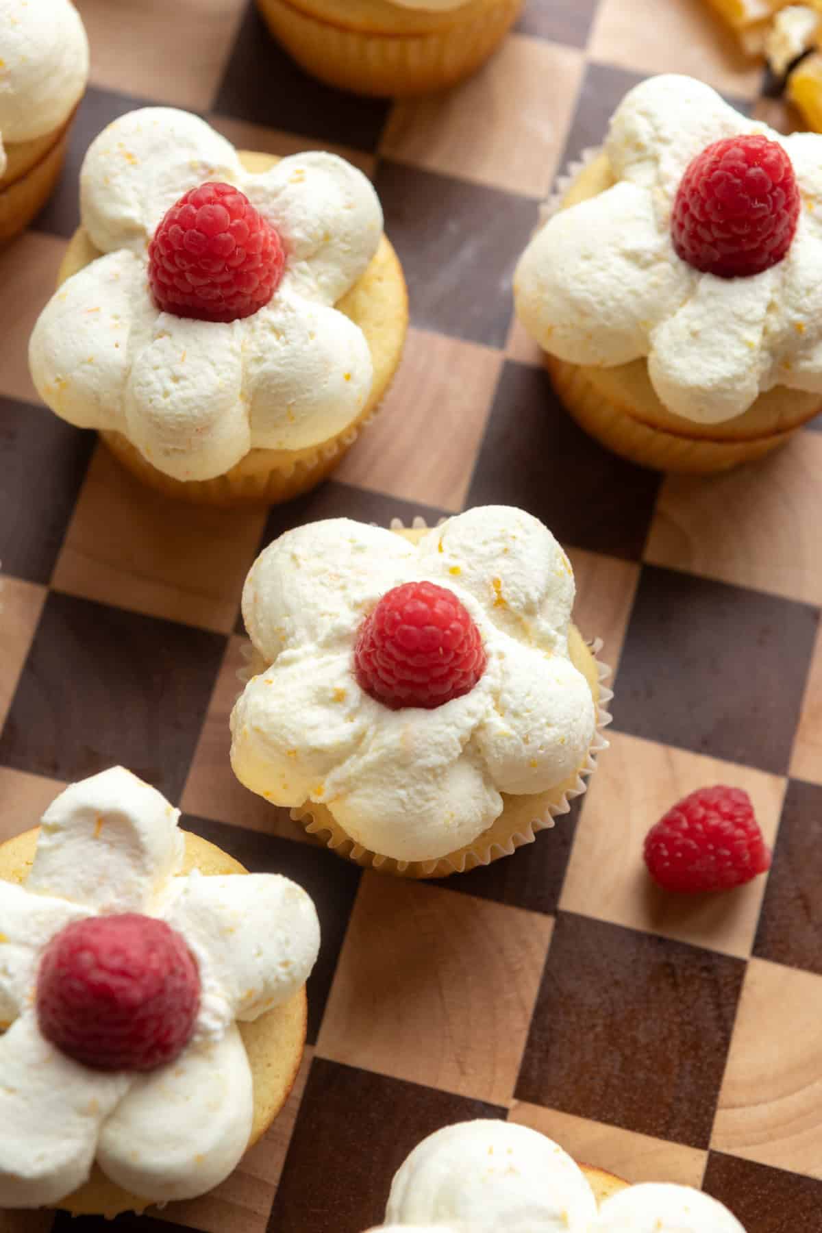 Close up of cupcakes garnished with fresh raspberries.