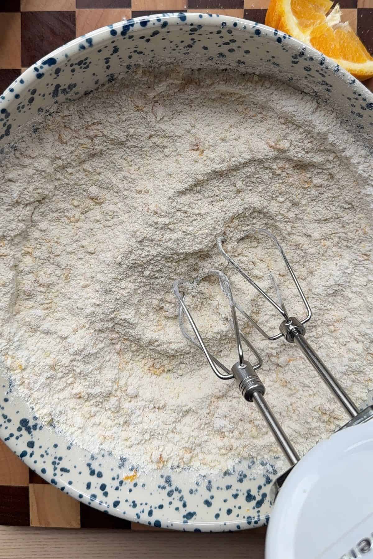 Dry ingredients in a bowl with a hand mixer.