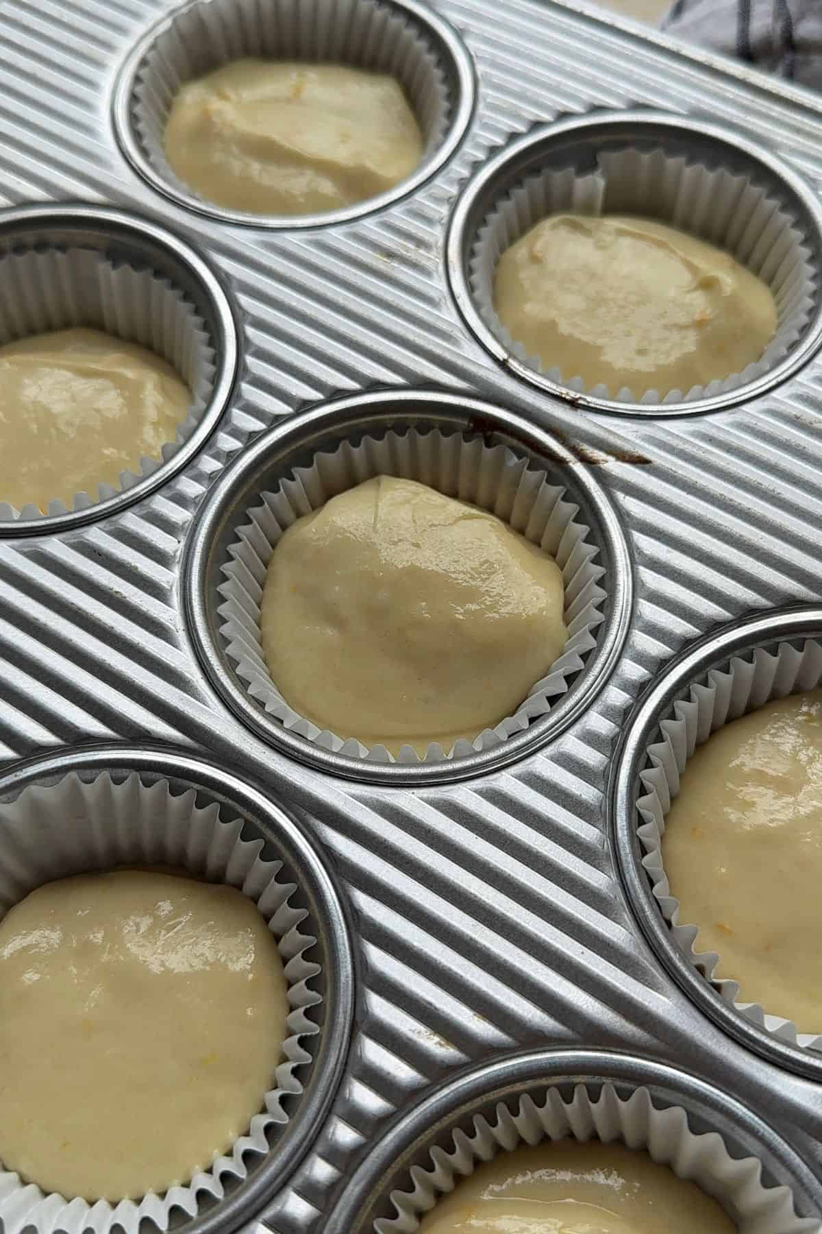 Unbaked orange cupcakes in a cupcake pan.