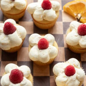 Raspberry orange cupcakes on a wood checkered surface.